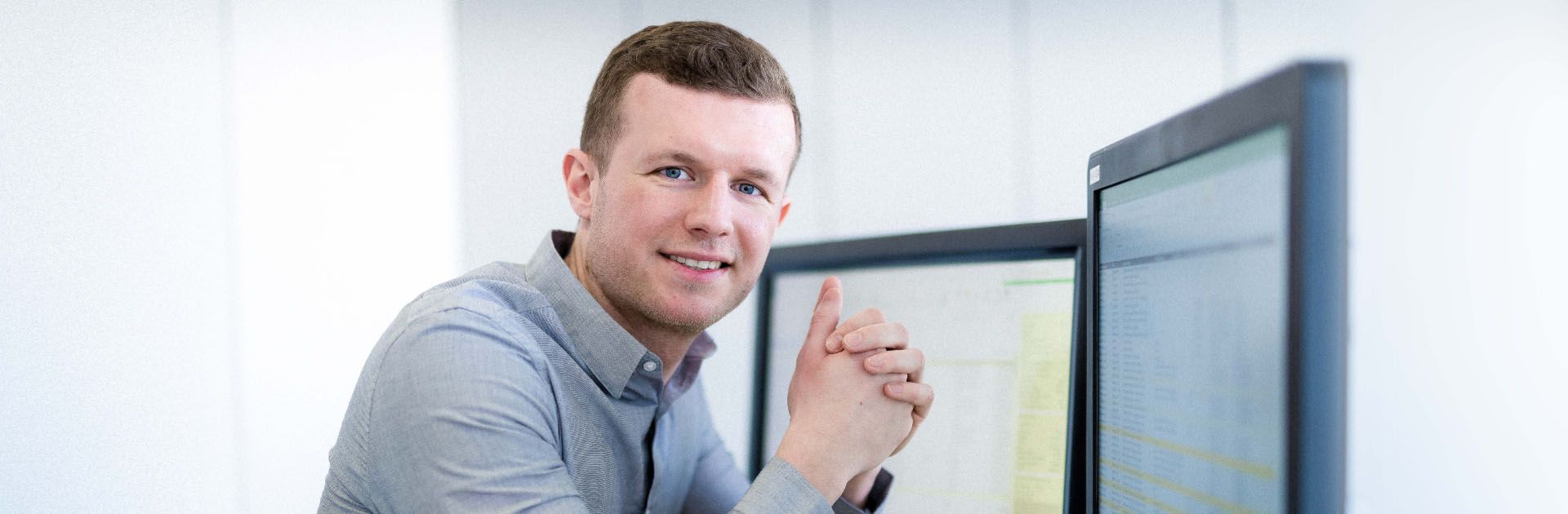 Junger Mitarbeiter aus der Büroabteilung lächelt in die Kamera