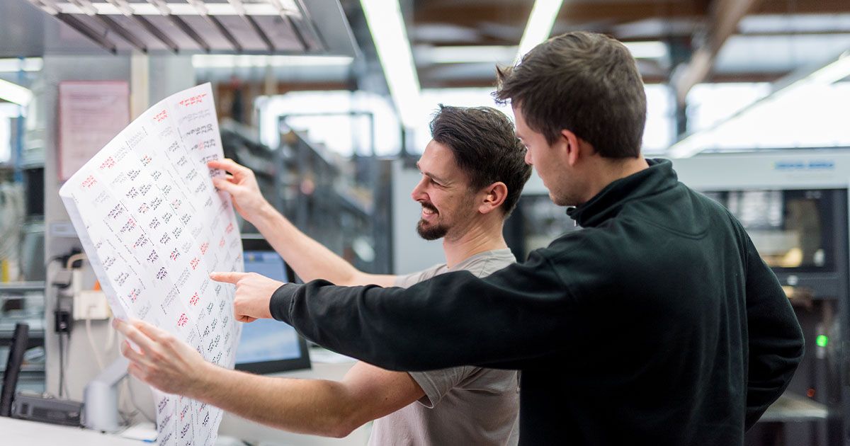 Zwei Mitarbeiter unterhalten sich gut gelaunt über einen druckfrischen Kalender